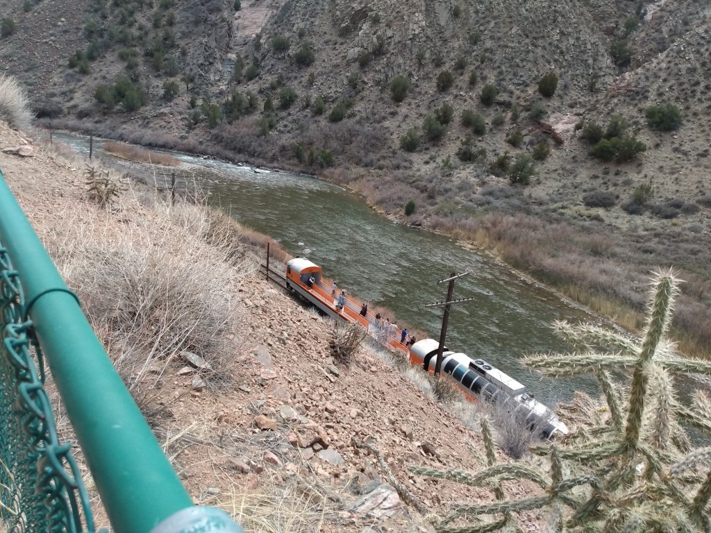 Photo looking down on train running along the river