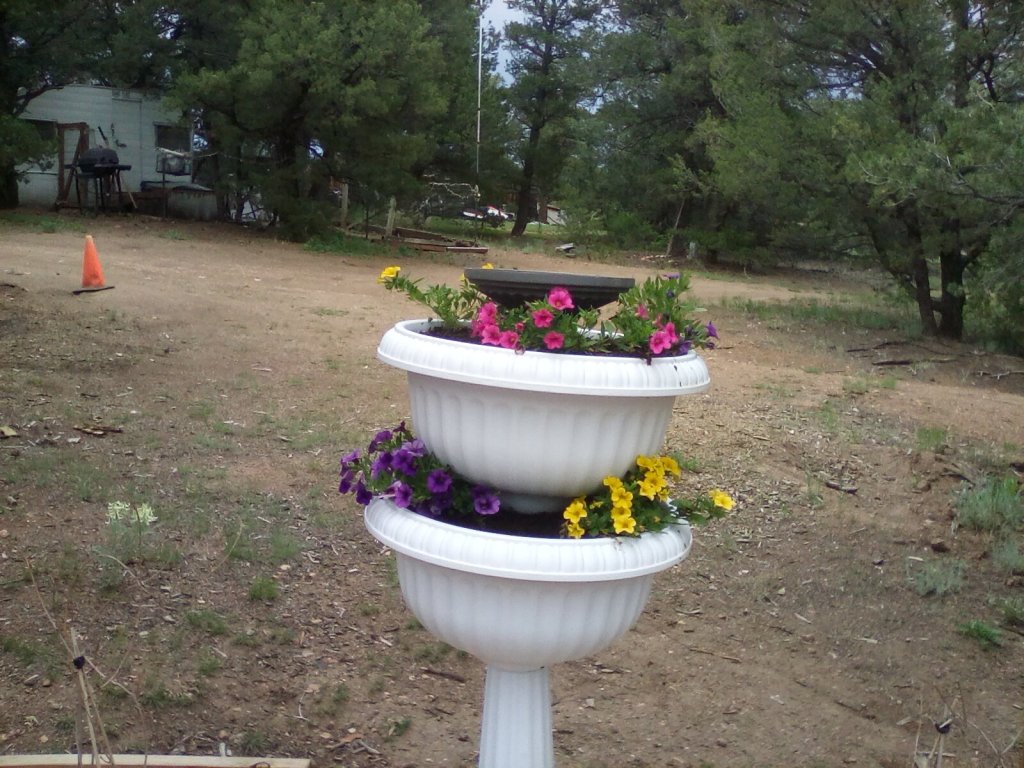 A double teired planter with pink, yellow and purple flowers