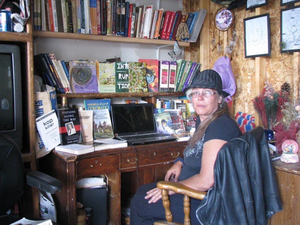 Photo of author KAye Lynne Booth at her desk, surrounded by books