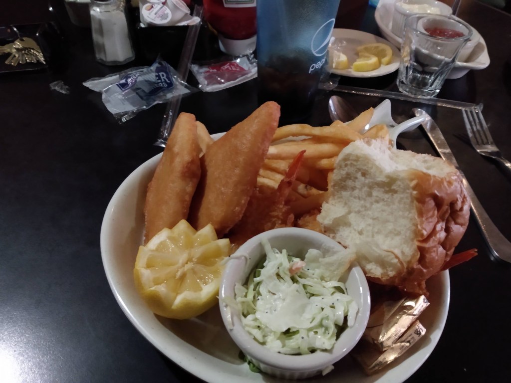 Fish and Chips coleslaw and a roll with lemon garnish