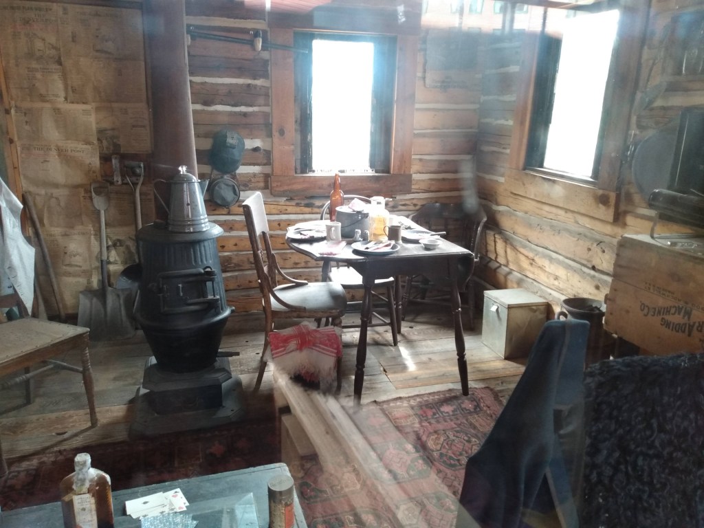 Pot belly stove with coffee pot on top in room with table and chairs