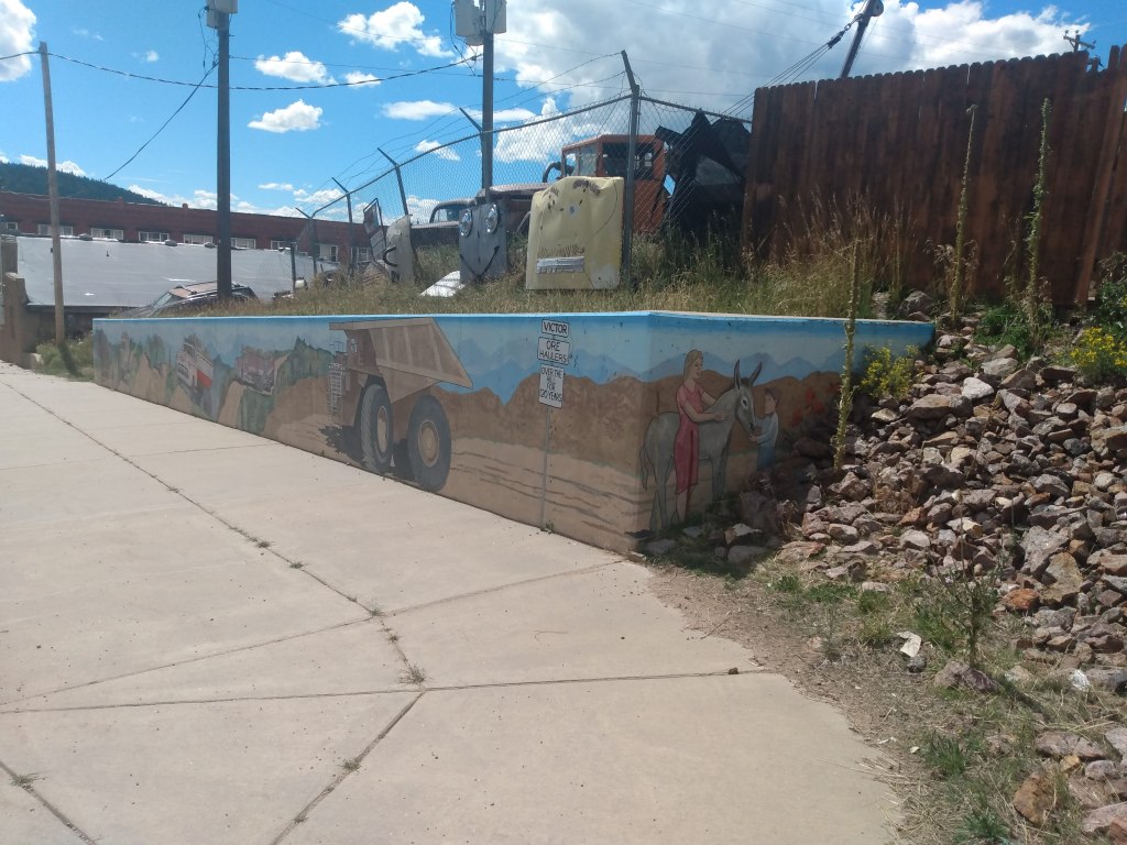 Retaining wall in Victor, Colorado with mining trucks and donkeys painted on it.